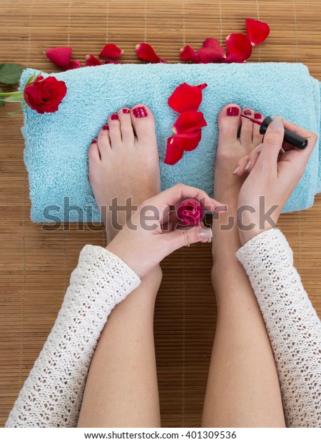Top view of woman applying nail varnish to toe nails\
at home