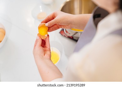 Top View. A Woman Cook Breaks An Egg And Separates Yolks From Proteins To Prepare Cream Or Dough In A Mixer Bowl. Cooking Courses And Dessert Recipes. Family Business. Online Lessons For Cooks.