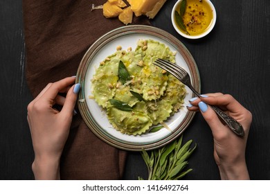 Top View Of Woman Eating Delicious Green Ravioli With Sage And Pine Nuts At Black Wooden Table