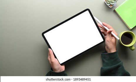 Top view of woman in green sweater holding digital tablet with blank screen and stylus pen on green table. - Powered by Shutterstock