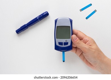 Top View Of Woman Hand Holding Glucose Meter With Blooded Test Strip With Empty Screen To Fill Your Datas On White Background