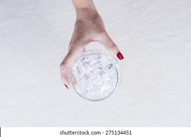 Top View Of A Woman Hand Holding A Balloon Glass Full Of Ice Cubes On The Glass Chilling Process On A Gin Tonic Preparation Session - Focus On The Ice Cubes