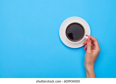 Top View Of Woman Hand Holding A Cup Of Coffee Over Flatlay