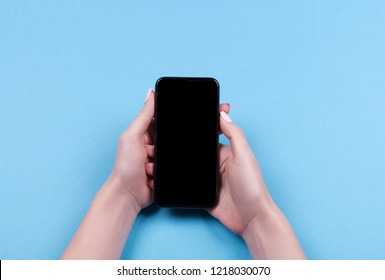 Top view of a woman hand using phone on blue background.  