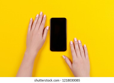 Top view of a woman hand using phone on yellow background.  