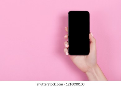 Top View Of A Woman Hand Using Phone On Pink Pastel Background.