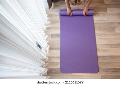 Top View Of Woman Hands Folding Purple Yoga Or Fitness Mat After Working Out At Home. Yoga Mats Are Specially Fabricated Mats Used To Prevent Hands And Feet Slipping During Practice Yoga.