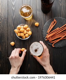 Top View Of Woman Hands Holding Glass Of Beer And Cheese Snack, Black Wooden Background. Flat Lay