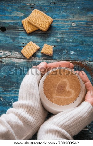 Top view of a woman hands  holding hot cappuccino