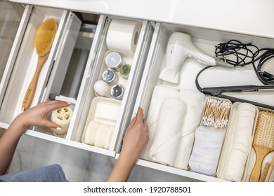 Top view of woman hands neatly organizing bathroom amenities and toiletries in drawer or cupboard in bathroom. Concept of tidying up a bathroom storage by using Marie Kondo's method. - Shutterstock ID 1920788501
