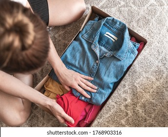 Top View At Woman Holding Clothes With Donate Box In Her Room, Donation Concept.