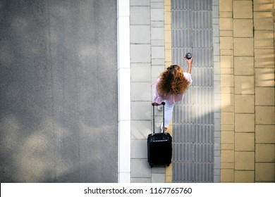 Top view of woman holding coffee to go and luggage while going to the station/airport. - Powered by Shutterstock