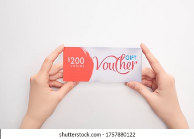 Top View Of Woman Holding Gift Voucher With Values Lettering On White Background