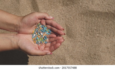 Top view of a woman holding microplastics in her palms at the beach. Volunteer help. Non-recyclable materials. Selective focus of microplastics. Global warming and climate change concept         