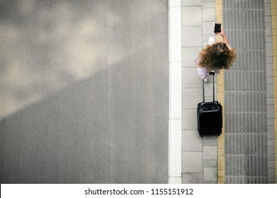 Top view of woman holding smart phone and luggage while going to the station/airport. - Powered by Shutterstock