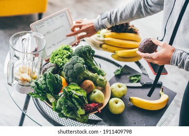 Top View Of Woman Holding Tablet With Calorie Counting App On Kitchen Table Near Fresh Vegetables. 