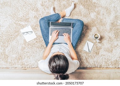 Top view of woman with laptop sitting on the floor at home