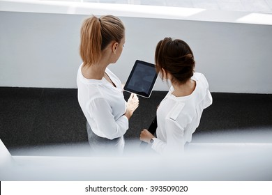 Top view of woman lawyer is holding touch pad with blank copy space screen, while is standing with secretary in modern interior. Two female office worker are watching news in web via digital tablet - Powered by Shutterstock