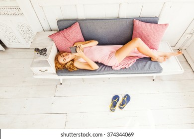 top view of woman lying on a couch and using phone