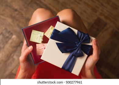 Top View Woman Opening A Present With Blue Ribbon With Three Gift Boxes Inside On Her Knees