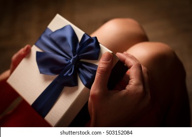 Top View Woman Opening A Present With Blue Ribbon With Three Gift Boxes Inside On Her Knees