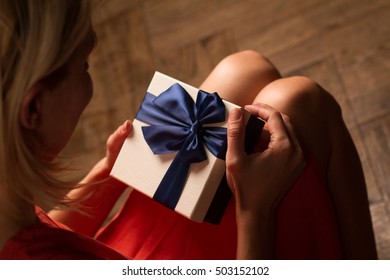 Top View Woman Opening A Present With Blue Ribbon With Three Gift Boxes Inside On Her Knees