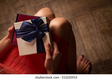 Top View Woman Opening A Present With Blue Ribbon With Three Gift Boxes Inside On Her Knees