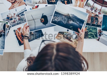 Top view of a woman photographer working in studio. Female photographer checking image prints.