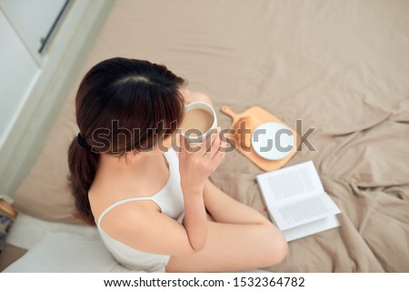 Top view of woman relax on bed with drinking coffee and reading book.
