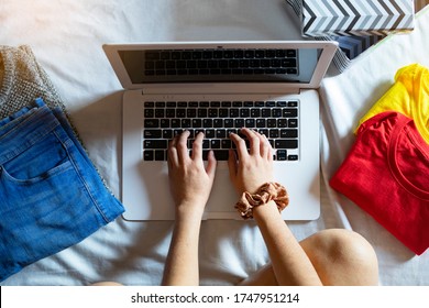 Top View Of A Woman Selling Clothes With Her Computer At Home. Concept Of Selling Clothes Online. Second-hand Clothes.