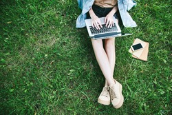 Top View Of Woman Sitting In Park On The Green Grass With Laptop, Notebook And Smartphone, Hands On Keyboard. Computer Screen Mockup. Student Studying Outdoors. Copy Space For Text