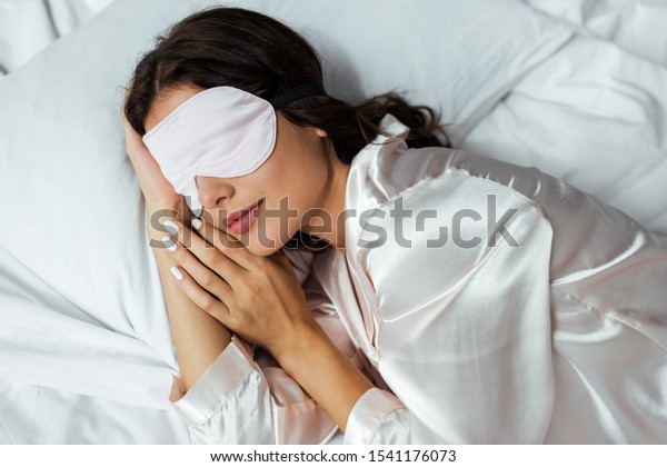 top view of woman in sleeping mask lying in bed at\
morning 