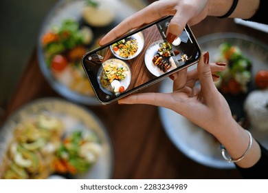 Top view woman taking photo of food with phone in hand. Food photography with phone. Social media photography.