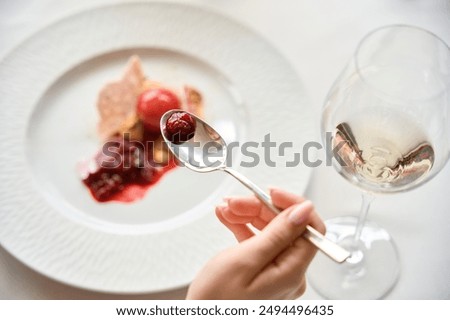 Top view of woman tasting dessert holding spoon in the restaurant, wine glass on the table
