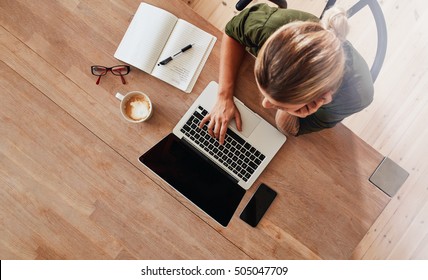 Top View Of Woman Using Laptop While Sitting At Cafe Table With Laptop, Mobile Phone, Diary, Coffee Cup And Glasses. Female Surfing Internet At Coffee Shop.