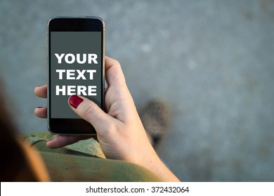 Top view of woman walking in the street using her mobile phone with copy space. All screen graphics are made up. - Shutterstock ID 372432064