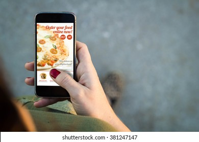 Top View Of Woman Walking In The Street Using Her Mobile Phone To Order Food Online With Copy Space. All Screen Graphics Are Made Up.