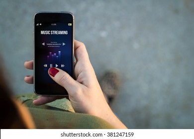 Top View Of Woman Walking In The Street Using Her Mobile Phone To Listen Music Streaming With Copy Space. All Screen Graphics Are Made Up.