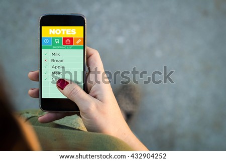 Top view of woman walking in the street using her mobile phone with note app. All screen graphics are made up.