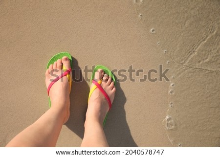 Top view of woman wearing flip flops on sandy beach, closeup