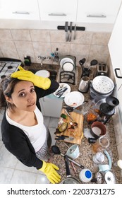 Top View Of Woman Wearing Gloves Exhausted Because Of Her Messy Kitchen. Vertical Photography