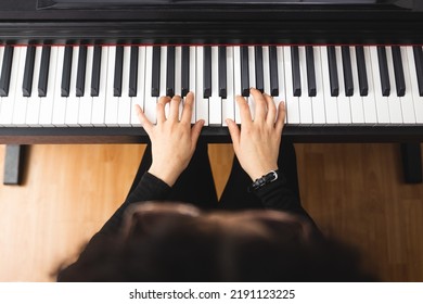 Top view of woman's hands playing piano by reading sheet music.  - Powered by Shutterstock