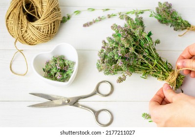 Top view of a womans hands tying thyme herb sprigs into a bundle using jute rope in the kitchen. Harvesting and drying fragrant herbs in summer, natural medicine, fragrant spice, culinary ingredient. - Shutterstock ID 2177211027