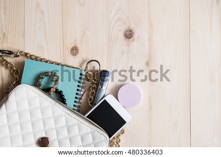 Top view of Women bag and lady stuff with copyspace on wooden background