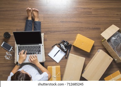 Top view of women working laptop computer from home on wooden floor with postal parcel, Selling online ideas concept