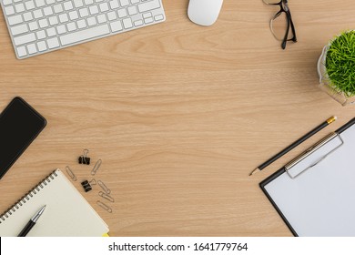 Top view Wood office desk. Flat lay Workspace with eye glasses, tree pot, keyboard, mouse computer, smart phone, clipboard, notebook, pencil, pen office supplies on wooden background - Shutterstock ID 1641779764