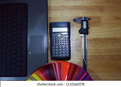 top view wood table with computer notebook and vernier, calculator and color chart and brush, engineering concept
