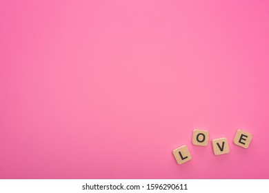 top view of wooden blocks with love lettering isolated on pink
