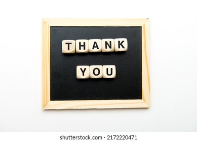 Top View Of Wooden Cubes With Thank You Inscription On Black Chalk Board.