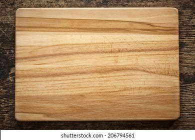 Top View Of Wooden Cutting Board On Old Wooden Table